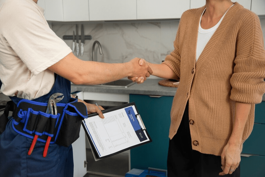 Male plumber working with client to fix kitchen problems